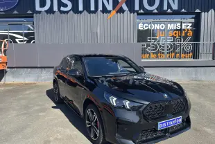 BMW X2 noir vue 3/4 avant droit, avec calandre noire et jantes alliage bicolores, stationnée devant un bâtiment Distinxion.