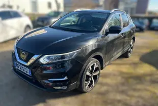 Vue 3/4 avant droit d'un Nissan Qashqai noir avec jantes alliage et calandre chromée dans un garage en bois.