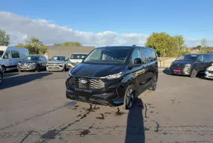 Ford Transit Fourgon Custom noir vu de 3/4 avant droit sur un parking en extérieur, avec jantes alliage sport.