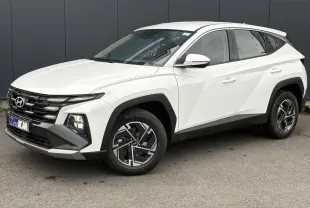 Vue 3/4 avant droite du Hyundai Tucson 2026 blanc Serenity avec jantes alliage 17 pouces et calandre noire distinctive.