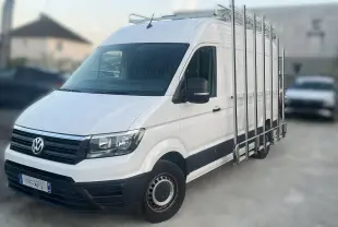 Volkswagen Crafter blanc vu en 3/4 avant droit avec porte-échelles latéral et calandre noire.