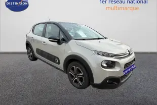 Citroën C3 beige vue 3/4 avant droit, avec protections latérales noires et jantes spécifiques, stationnée devant un mur blanc.