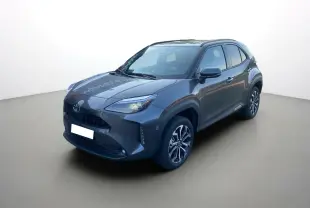 Toyota Yaris Cross hybride gris atlas vue 3/4 avant droit avec jantes alu 17 pouces et feux LED allumés.
