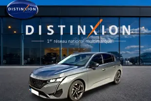 Peugeot 308 gris selenium vue 3/4 avant droit devant une vitrine Distinxion avec jantes alu noires.