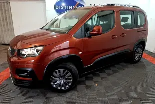 Peugeot Rifter BlueHDi 100 marron en 3/4 avant droit, avec barres de toit chromées et protections noires sur les bas de caisse.