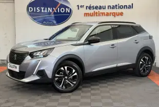 Peugeot 2008 gris clair en 3/4 avant droit, avec jantes noires et toit noir contrasté visible en intérieur showroom.