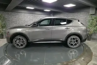 Vue de profil côté gauche de l'Alfa Romeo Tonale gris métallisé avec jantes alliage 18 pouces en showroom.