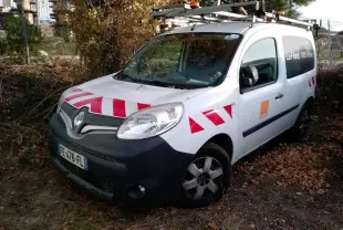 Renault Kangoo blanc vue 3/4 avant droit avec bandes rouges réfléchissantes sur capot et portières.