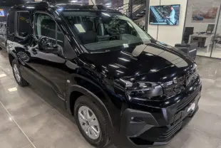 Vue 3/4 avant d’un Peugeot Rifter Allure 2026 noir Perla Nera, avec calandre et optiques modernes en showroom.