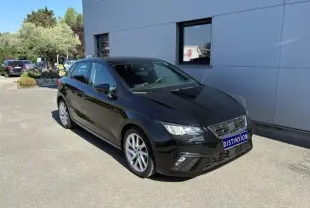 SEAT Ibiza 1.0 TSI 95 FR noire vue en 3/4 avant, stationnée devant un bâtiment gris par temps ensoleillé.