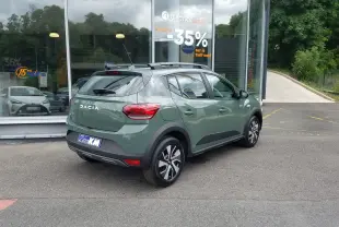 Vue 3/4 arrière droite d'une Dacia Sandero Stepway 2025 en Licken Kaki avec barres de toit et jantes modernes.