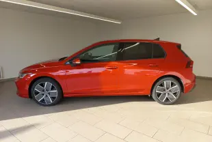 Profil côté gauche d'une Volkswagen Golf 2.0 TDI 150 DSG7 Style rouge métallisé avec jantes alliage 18 pouces dans un showroom.