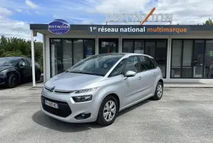 Citroën C4 Picasso gris aluminum vue 3/4 avant droit, stationnée devant un showroom Distinxion.