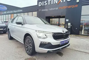 Vue 3/4 avant d’un Skoda Kamiq 2025 argent avec toit noir et jantes alliage 17 pouces, devant un showroom Distinxion.
