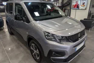 Peugeot Rifter gris Artense en 3/4 avant droit, avec calandre noire et jantes alliage bicolores visibles en showroom.