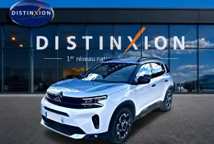 Citroën C5 Aircross blanc en 3/4 avant droit, avec jantes alu et barres de toit visibles devant showroom Distinxion.