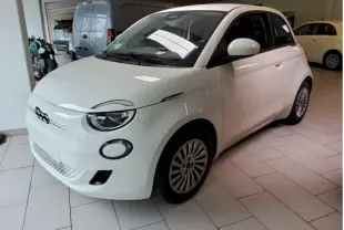 Vue 3/4 avant droite d'une Fiat 500 électrique blanche 2024 dans un showroom intérieur.