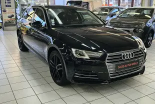 Audi A4 Avant noire vue en 3/4 avant droit, avec jantes noires et calandre chromée dans un showroom.
