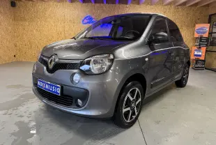Renault Twingo III gris en 3/4 avant droit, avec jantes noires et phares halogènes visibles en intérieur showroom.
