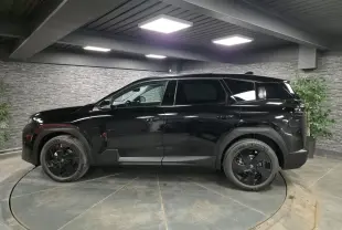Vue latérale gauche du SUV Citroën C5 Aircross noir brillant avec jantes alliage noires dans un showroom intérieur.
