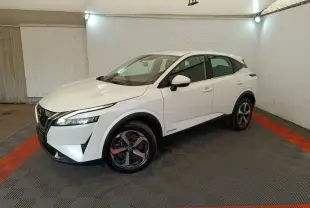Vue 3/4 avant droit du Nissan Qashqai e-Power blanc avec jantes alliage et feux LED dans un espace fermé.