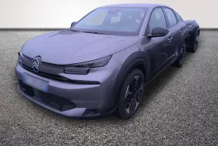 Vue 3/4 avant droite d'une Citroën C4 hybride gris foncé avec pluie visible sur la carrosserie.