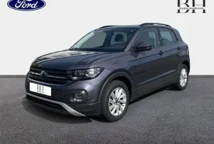 Volkswagen T-Cross gris cendré métallisé en 3/4 avant droit avec barres de toit et jantes alu visibles.