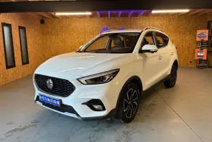 Vue 3/4 avant d’un MG ZS blanc 2022 dans un intérieur en bois, avec calandre noire et jantes noires distinctives.