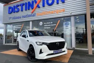 Vue 3/4 avant droite d'un Mazda CX-60 blanc nacré avec jantes noires, devant une concession Distinxion.