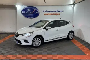 Renault Clio Business TCe 100 blanc vue 3/4 avant droit, phares LED allumés, stationnée en intérieur sur sol damier noir et orange.
