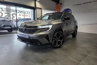 Renault Austral gris foncé en 3/4 avant droit, avec calandre à damier et jantes alliage noires diamantées.
