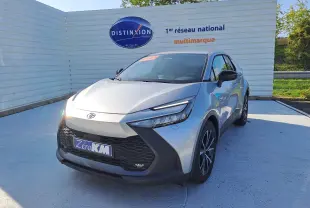 Toyota C-HR gris minéral en 3/4 avant droit, avec calandre noire et jantes bi-ton 18 pouces visibles.