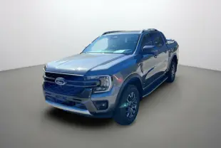 Ford Ranger Wildtrak gris carbone vu en 3/4 avant droit avec barres de toit et jantes alu 18 pouces.