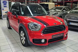 Vue 3/4 avant d'une MINI Cooper Countryman rouge avec bandes noires sur le capot, en showroom intérieur.