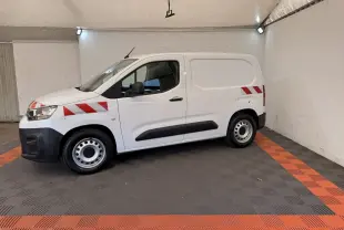Vue de profil côté gauche d’un Citroën Berlingo blanc 2019 avec bandes rouges diagonales sur l’aile avant et l’arrière.