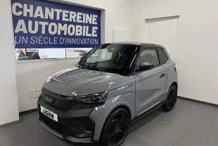 Vue 3/4 avant droite d'une Ligier JS50 gris clair avec toit noir et jantes noires en showroom.