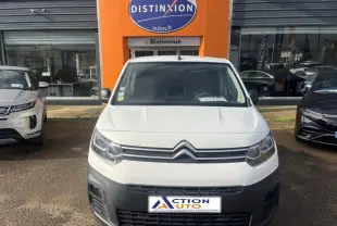 Vue de face d'un Citroën Berlingo Fourgon blanc Banquise avec calandre noire et pare-chocs gris devant un garage.