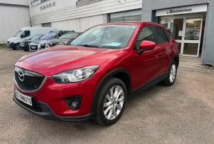 Mazda CX-5 rouge Soul Red métallisé en vue 3/4 avant droit, avec jantes alliage et calandre noire distinctive.