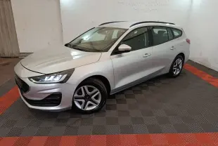 Ford Focus 1.0 EcoBoost gris clair vue 3/4 avant droit avec phares LED allumés dans un garage.
