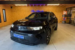 Opel Mokka noir vue 3/4 avant droit en intérieur, avec calandre Vizor et phares LED allumés.