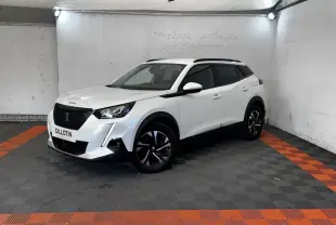Peugeot 2008 blanc en 3/4 avant droit, avec jantes noires et toit noir dans un garage éclairé.