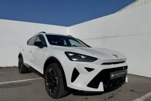Vue 3/4 avant droit d'une CUPRA Formentor blanc nacré avec toit noir et jantes alliage noires dans un parking extérieur.
