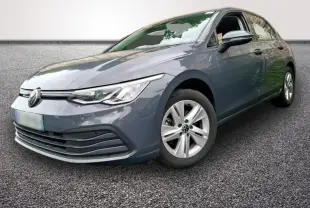 Volkswagen Golf gris clair vue 3/4 avant droit, avec jantes alliage et phares LED allumés.