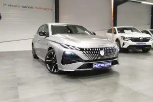 Vue 3/4 avant d'une Peugeot 308 gris Artense avec calandre lumineuse et jantes alliage noires en showroom.