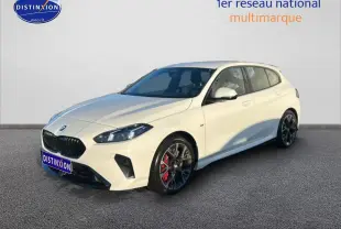 BMW Série 1 blanche alpin vue 3/4 avant droit, avec jantes 18 pouces bicolores et étriers rouges visibles.