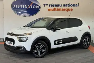 Citroën C3 blanche vue 3/4 avant droit, avec protections latérales noires et jantes stylisées bicolores.