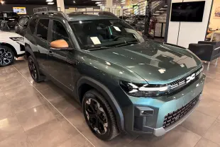 Vue 3/4 avant droit du Dacia Bigster Hybrid-G 150 4x4 en Vert Cèdre avec rétroviseurs bronze et jantes noires bicolores.