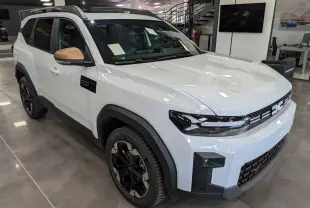 Vue 3/4 avant du Dacia Bigster blanc Glacier avec rétroviseurs bronze et jantes noires en concession.