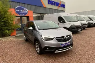 Opel Crossland X gris métallisé en 3/4 avant droit, stationné devant un concessionnaire Distinxion.