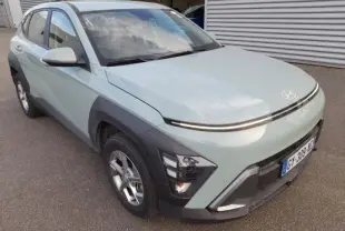 Vue 3/4 avant d’un Hyundai Kona 2024 Mirage Green avec phares LED et protections noires autour des roues.